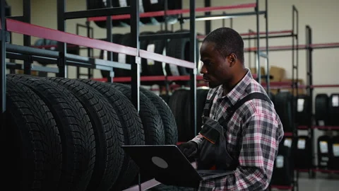 African American worker using laptop in tire warehouse Stock Footage 301557410