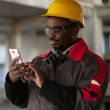 African american workman with smartphone at construction site Photos