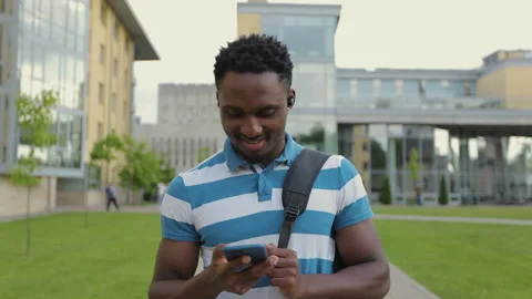 African American young man using phone walk on street listens to music in Stock Footage 155682076