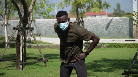 African american young runner man wearing surgical face mask stretching warm Stock Footage 146653498
