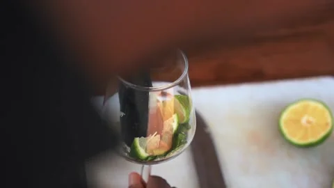 African bartender pressing lime in glass, mixing it with mint leaves. slowmo Stock Footage 230080326