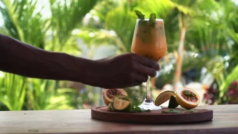 African bartender serving out passion fruit mojito in tropical background Stock Footage 230080370