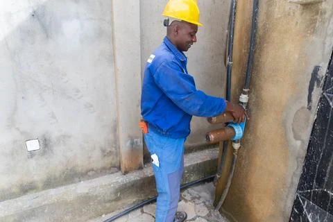 An African blue collar worker preparing to replace dirty rusty water filters Foto stock