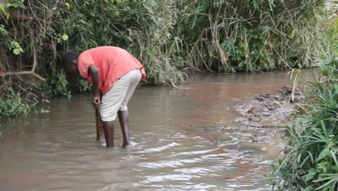 African Boy Digging Sand out of Polluted Stream (HD) Stock Footage 7375497