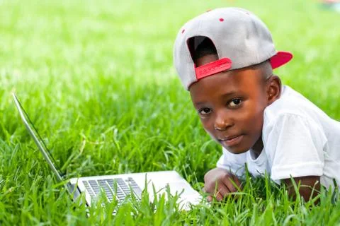 African boy laying with laptop on grass. Foto stock