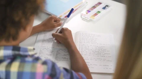 African boy is learning language by writing correct answer in epmty space in Stock Footage 114018837