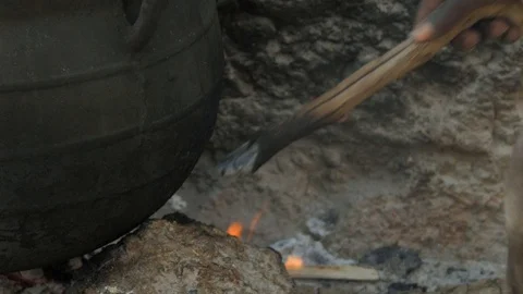 African Boy Pulls Buring Stick from Fire to Burn Bamboo co Stock Footage 115737357