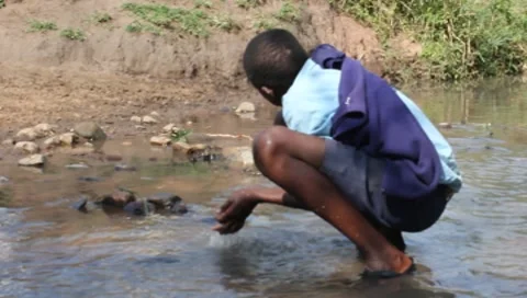 African Boy in School Clothes Drinks from Polluted Stream (HD) 스톡 동영상 7139033