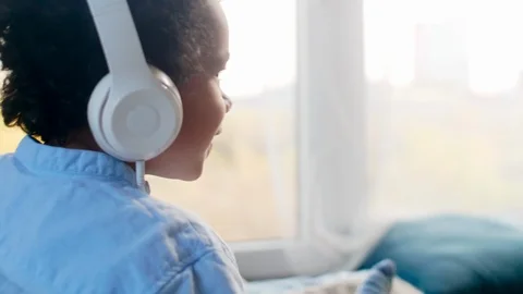 African Boy Sitting on Bed and Enjoying Music on Smartphone Видео 101042308