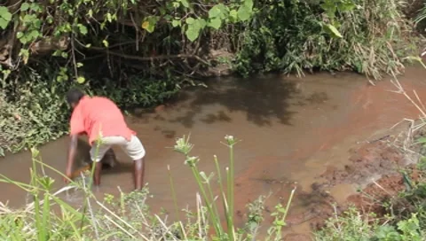 African Boy Throwing Sand from Polluted Stream (HD) Stock Footage 7378940
