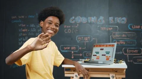 African boy use laptop to code program and turn around to wave hand. Edification 스톡 사진