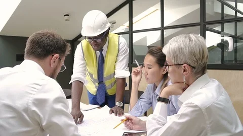 African builder presenting house blueprint to colleagues on briefing in meeting Stock Footage 99045918