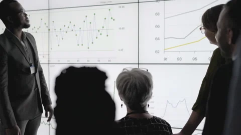 African businessman explaining data on a digital multiscreen office wall Stock Footage 138984687