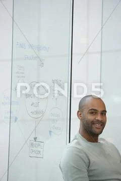 African businessman next to clear dry erase board Stock Photos