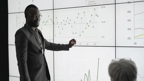 African businessman presenting data on a digital multiscreen office wall Stock Footage 138984641
