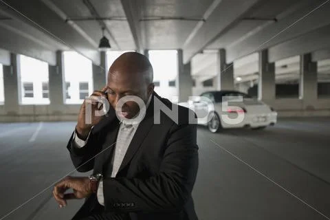African Businessman Talking On Cell Phone In Parking Garage
