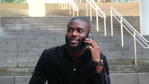 African businessman talking on smartphone while sitting on outdoor stairs i.. Stock Footage 279800577