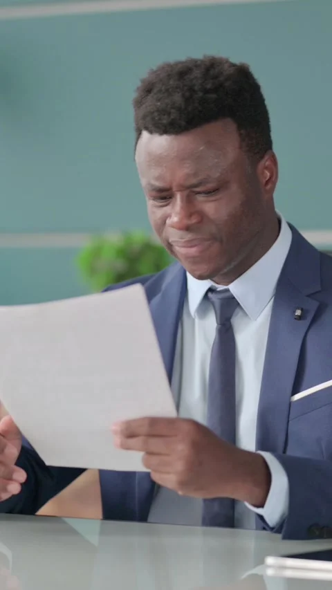 African Businessman Upset while Reading Documents in Office, Vertical Video Stock Footage 339574792