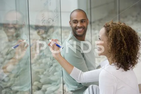 African businesswoman writing on clear dry erase board Stock Photos