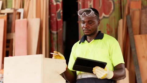 African carpenter analyzing design sketches on digital tablet in workshop  Stock Footage 346733930