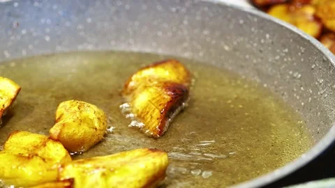 African chef frying plantain tree fruit with extra virgin olive oil on induct Vídeo Stock 220075375