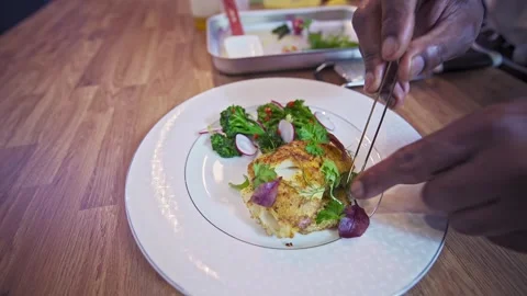 African chef plating pan seared cod on a white plate Stock Footage 267008256