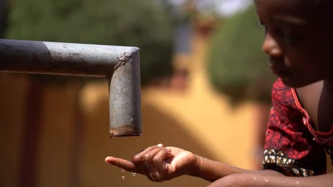 African Child Counting Drops At A Water Pump Stock Footage