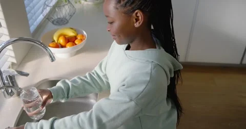 African child holding glass while turning faucet filling to drink at sink, 스톡 동영상 342067765