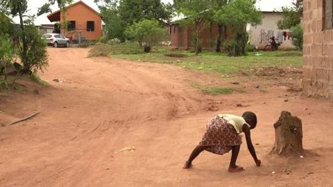 African child picking up trash from the ground in rural village Stock Footage 230078643