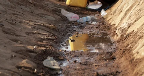 African children using a large bottle to fill water from a dirty water source Stock Footage 116302638