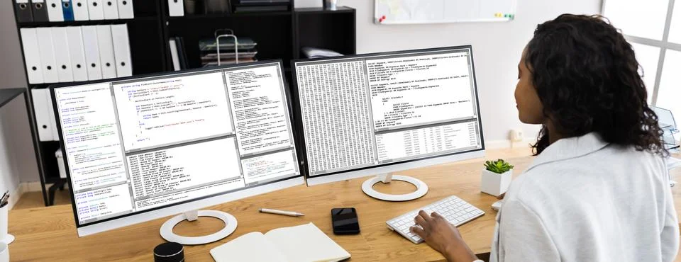 African Coder Using Multiple Computer Screens Foto stock
