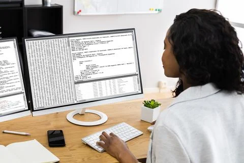 African Coder Using Multiple Computer Screens Foto stock