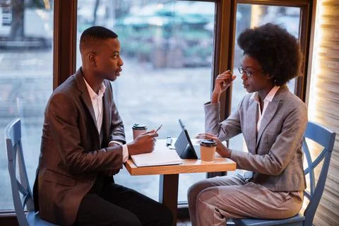 African colleagues discussing working issues at cafe Stock Photos