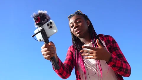 African content creator using mobile to record outdoors Stock Footage 263013706