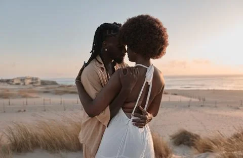 African couple hugging on beach at sunset Stock Photos