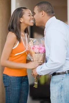 African couple rubbing noses over bouquet of flowers Fotos Stock