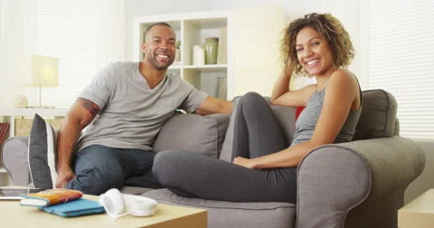 African couple sitting on couch smiling Video stock 44498499