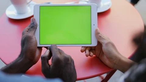 African couple sitting at table with cups of coffee and holding digital tablet Stock Footage 81835783