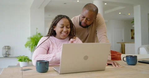 African couple sitting at table in kitchen, checkout appearing on laptop, woman Stock Footage 340674243