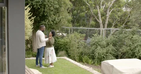 African couple standing yard, man proposing with ring while holding hands, Stock Footage 342363243