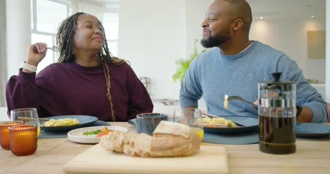 African couple at table eating bread woman looking playful lifting fork man Vídeos de archivo 340653954