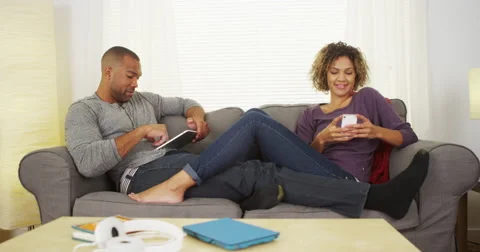 African couple using electronic devices on couch Stock Footage 44498091