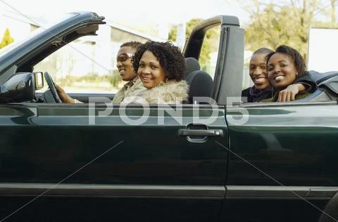 African couples driving in convertible car Stock Photos