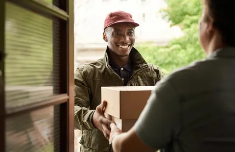 African courier smiling while delivering packages to a client Stock Photos