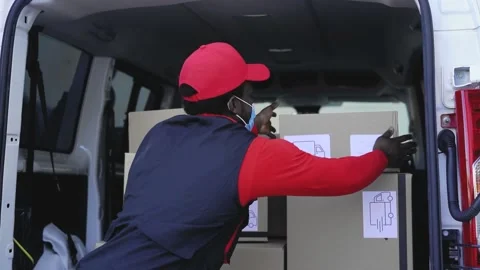 African delivery man loading boxes in the truck while wearing face mask Stock Footage 148934017