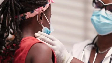 African doctor checking lymph nodes of girl child during pediatric examination 스톡 동영상 346730864