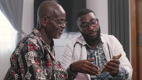 African Doctor Using Smartphone to Show Medical Information to Senior Patient Видео 346007462