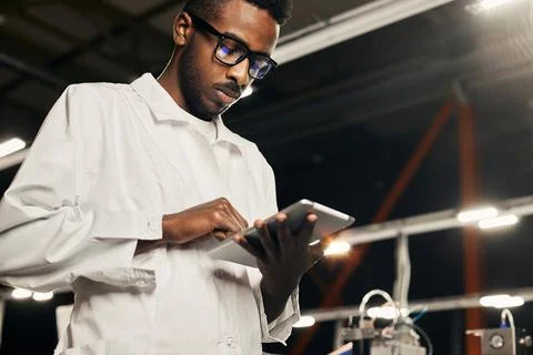 African engineer programming equipment with tablet at factory Stock-Fotos