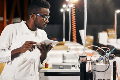 African engineer programming equipment with tablet at factory Stock-Fotos