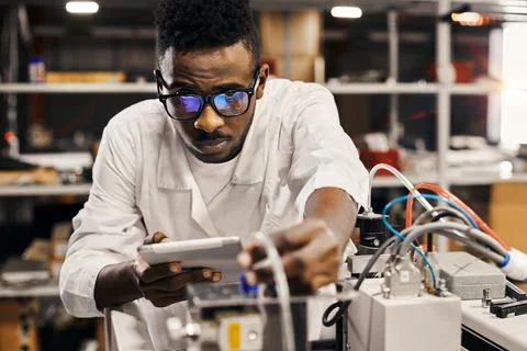 African engineer programming equipment with tablet at factory Stock-Fotos